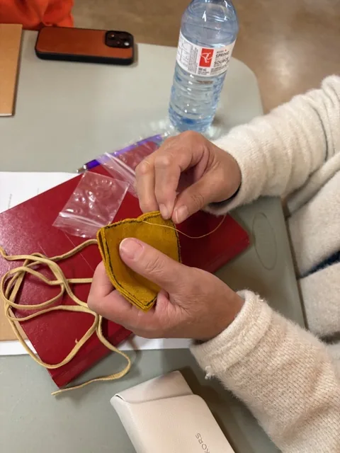 Hands working with materials during medicine-pouch making at the Wellness Gathering.