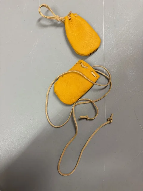 Handmade yellow leather pouches with drawstring cords from medicine-pouch making at the Wellness Gathering.