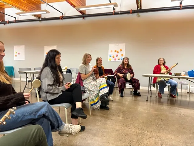 Participants seated together with hand drums and percussion instruments during the Wellness Gathering.